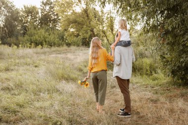 Genç ebeveynler ve kızları sonbaharın başlarında doğada yürürler. Ebeveynlerden koruma. hafta sonu