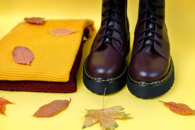 Sarı arka planda bordo çizmeler ve sonbahar kazakları.