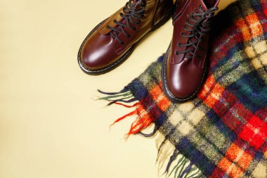 Sarı sonbahar arka planında kareli eşarp ve sonbahar çizmeleri