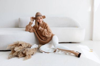 Sonbahar kıyafetleri içinde şık bir model ve hafif bir stüdyoda kuru çiçekler. Sonbahar posteri. Metin için boş alan