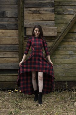 Kırmızı elbiseli genç bir vampir. Eski bir karavanın arka planında kaygı verici bir şekilde gülümseyen kız..