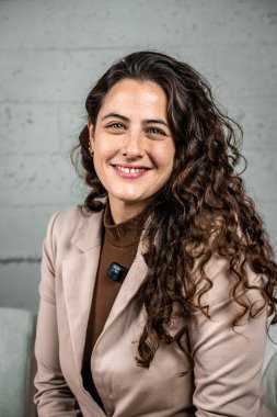 Kıvırcık saçlı ve burun halkalı, gülümseyen kendine güvenen bir iş kadını. Kurumsal ortamlarda profesyonelliği, başarıyı ve liderliği temsil etmek