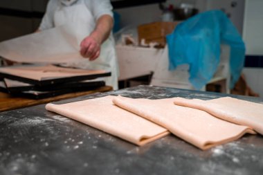 Ticari bir mutfakta hamur işi hazırlayan hamur işi şefleri metal bir yüzey üzerinde, zanaatkar pişirmeye hazır.