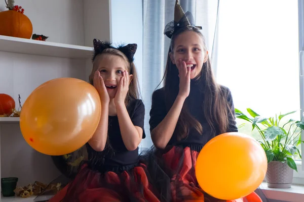 Ragazze divertenti in costume da strega di Halloween con palloncini sono felicemente sorpresi. — Foto Stock