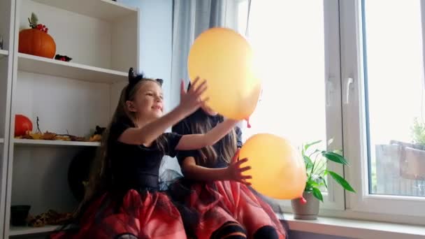 Две юмористки в костюмах ведьм на Хэллоуин играют с шариками — стоковое видео