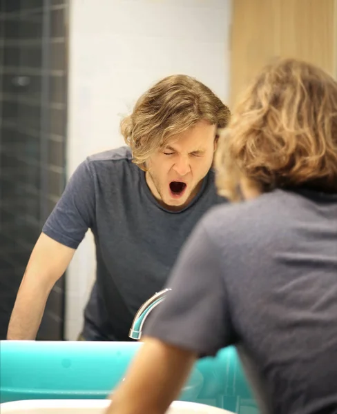 young man looking in the mirror,combing his hair,looking at problems on face.