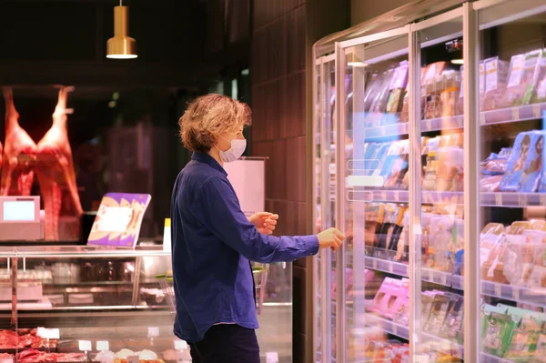 Supermarket shopping, face mask and gloves,Young man shopping in supermarket, reading product information.