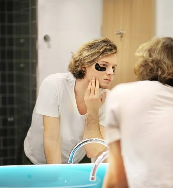 young man applying facial mask. Dark Circles.Eye patches..