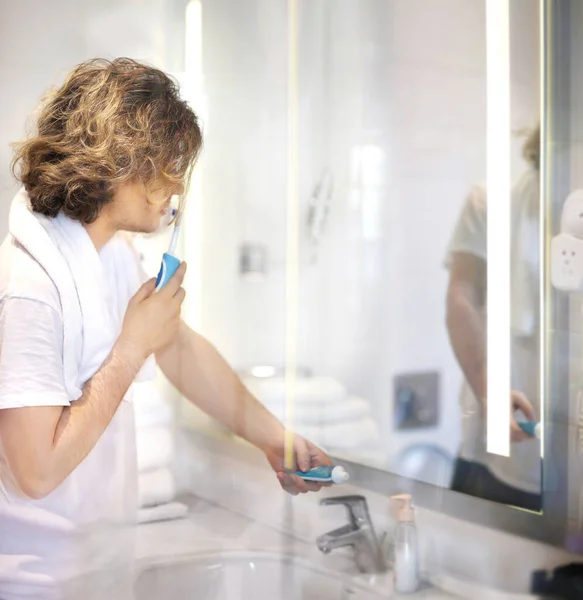 young man looking in the mirror,applying facial cream in bathroom while looking at mirror.