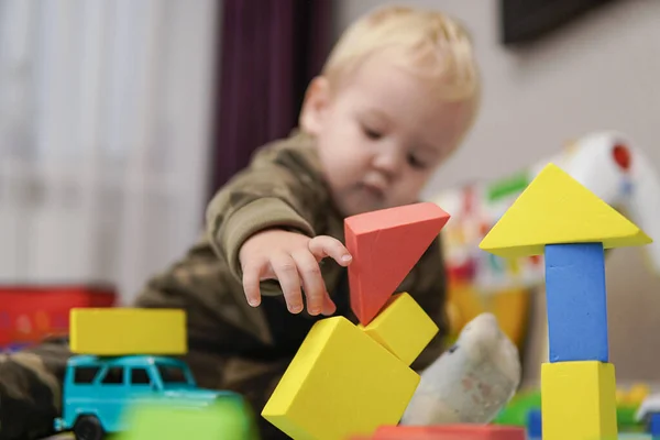 Little boy with blond hair ruined a house of cubes. high quality