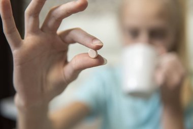 Kız hapı tutuyor ve ilaç içiyor. Yakın plan. yüksek kalite