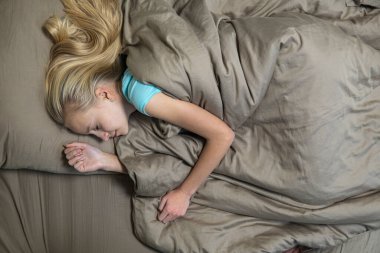 Sarı saçlı genç kız kahverengi yatakta uyur. yüksek kalite