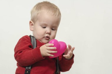 Kırmızı ceketli çocuk pembe kalbi tutuyor. yüksek kalite