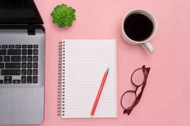 Masanın üstünden manzaralı düz bir masa. Pembe arka planda çalışan uzay not defteri, dizüstü bilgisayar, telefon ve kahve fincanı. yüksek kalite