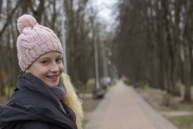 Bir bahar parkında sarı saçlı genç bir kızın portresi.