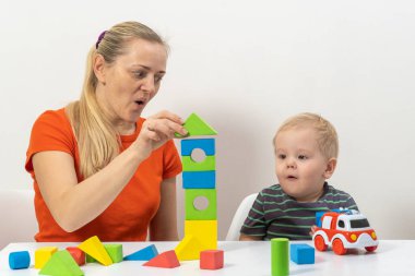 Anne ve oğlu küp oynuyorlar ve parlak arka plana gülüyorlar.