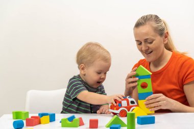Anne ve oğlu küp oynuyorlar ve parlak arka plana gülüyorlar.