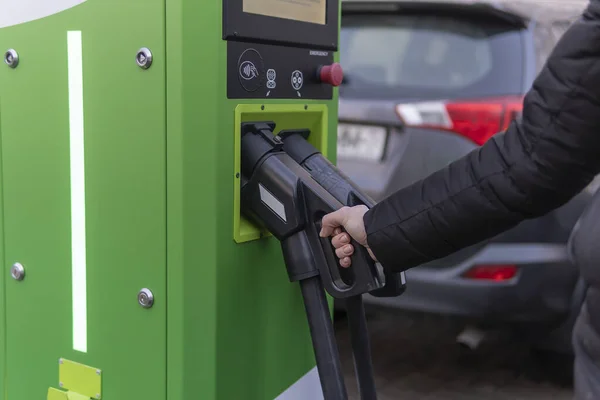 Girl to charge electric car. Hold in hand a cable to charge an electric car