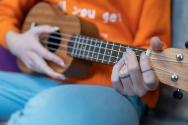 Yakın plan. Kızın elleri Hawaii müzik aleti ukulele çalıyor.