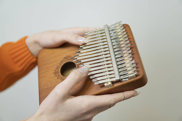 женские руки держат инструмент африканского кальмара на светлом фоне