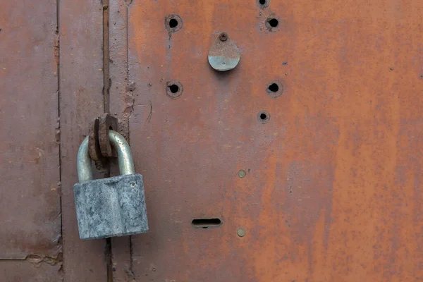 Kapıda eski kilit var. Eski bir çiftlik evinin kapısına kilit vurun. Gerçek köy tarzı. Yakın plan. Kilide odaklan