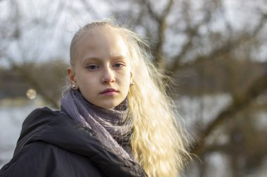 Bir bahar parkında sarı saçlı genç bir kızın portresi.