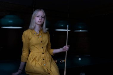 Moda ve eğlence konsepti. Bilardo havuzunda poz veren çekici genç bir kız. Çekici, modaya uygun bir kadın eğlence için zaman harcıyor.