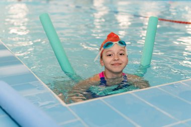 Mutlu kız havuz şehriyesiyle yüzmeyi öğreniyor..