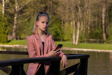 Parkta akıllı telefondan konuşan güzel bir genç kadın..