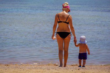 Anne ve oğul denizin kıyısında duruyor..