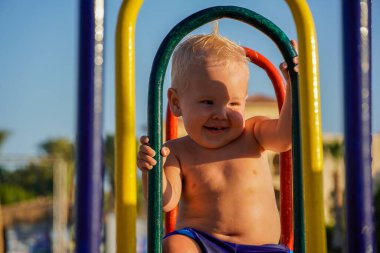 Sarı saçlı küçük çocuk salıncağa otur ve gül..