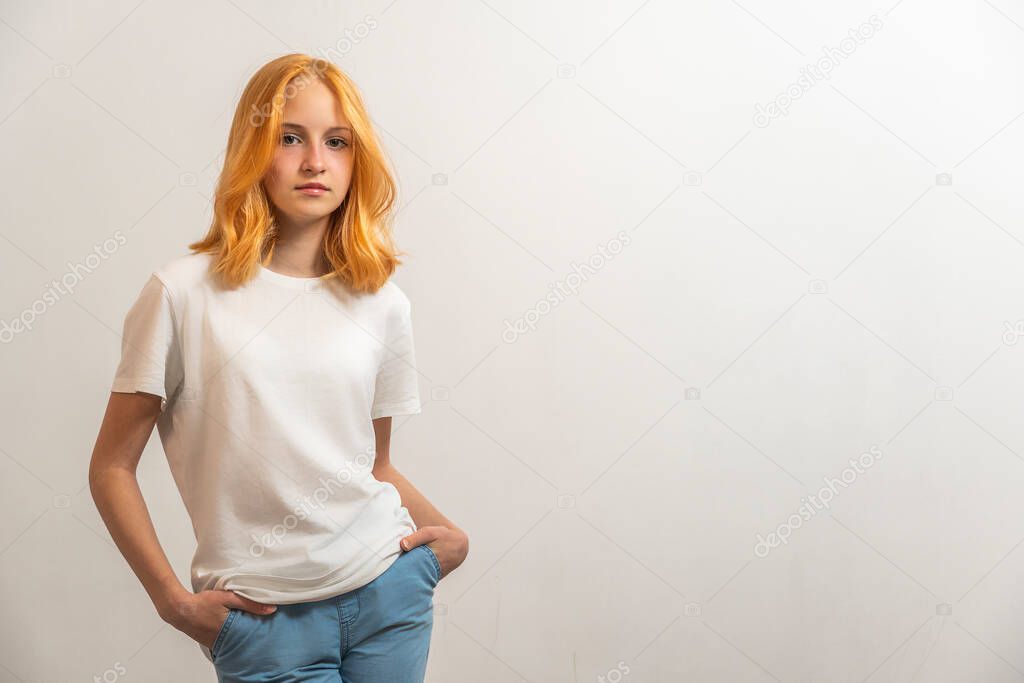 Portrait of a teenage girl with red hair and a white T-shirt on a light background.