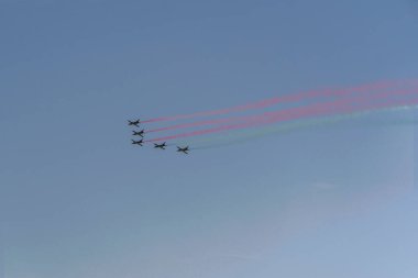 Beş uçak gökyüzünde uçuyor ve renkli dumanlar bırakıyor.