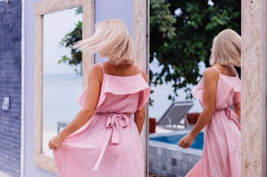 Lüks zengin villasında pembe elbiseli bir kadının romantik portresi.