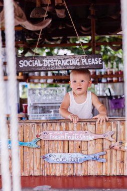 Küçük bebek Tayland 'da tatilde ve barında sosyal mesafe tabelası var..