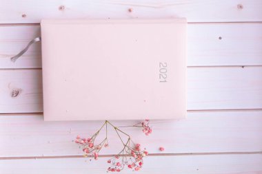 Şirin pembe çiçekli günlük pembe düzenleyici. Beyaz pembe ahşap arka planda 2021 yazıyor.. 