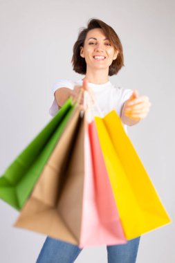 Beyaz arka planda alışveriş torbaları olan Avrupalı bir kadının stüdyo fotoğrafı