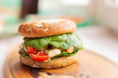 Tahta bir tahtanın üzerinde, Kral karidesli, feta peynirli ve sebzeli hamburger.