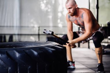 Yakışıklı, sakallı, spor salonundaki güçlü kaslı adam. Tek model, sıkı çalışıyor, lastikle Hummer çarpması eğitimi alıyor.