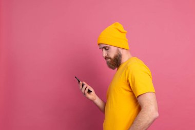 European handsome happy cheerful man with mobile phone pink background