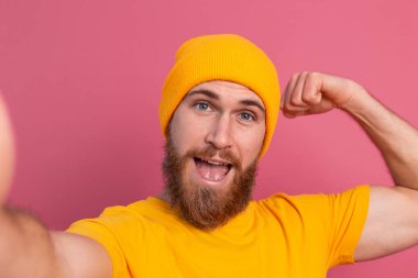 Strong handsome muscular happy cheerful man casual style take  photo selfie on pink background