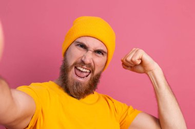 Strong handsome muscular happy cheerful man casual style take  photo selfie on pink background