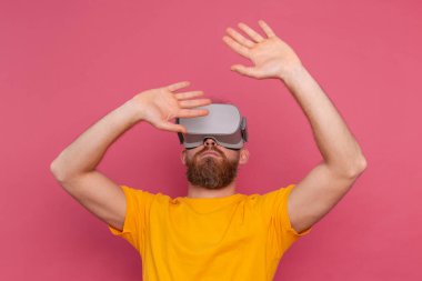 Handsome positive bearded man touching air in vr glasses studio background
