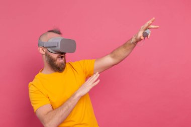 Korkmuş oyuncunun portresi, stüdyo arka planında VR gözlük takan tişörtlü sakallı adam.