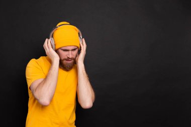 Handsome man in casual dancing with headphones isolated on black background