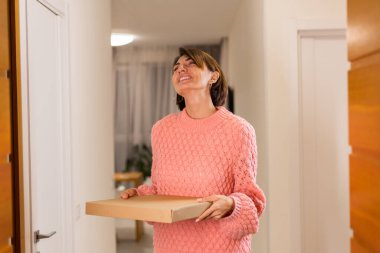 Tıbbi beyaz maskeli kadın teslimatçıdan yemek alıyor.