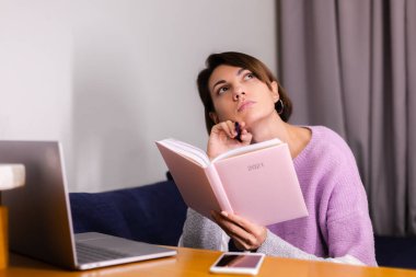 Woman at home with notepad notebook thinking about plans