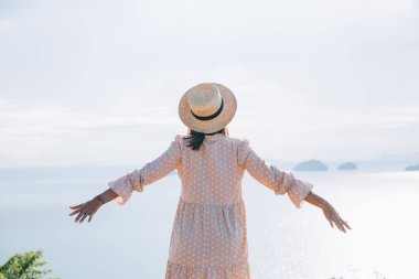 Happy woman in summer cute dress and straw hat on vacation in tropical exotic country