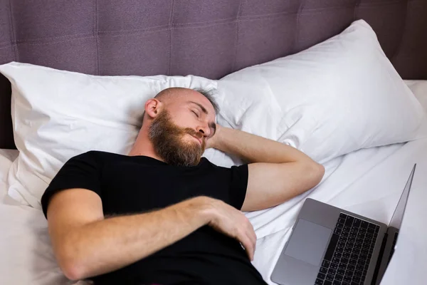 Man in bedroom on bed fell asleep in front of lapto