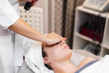 Güzellik salonundaki kadın müşteri güzellik uzmanından elle masaj alıyor. 